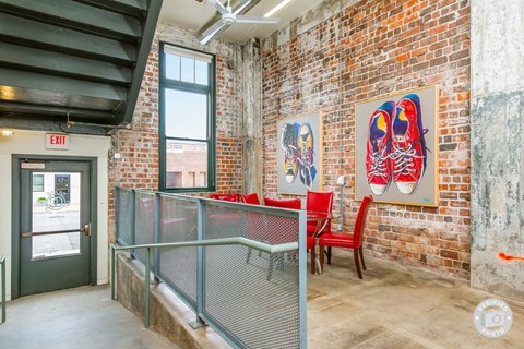 A room with a red chair and a painting of a pair of red shoes on the wall.